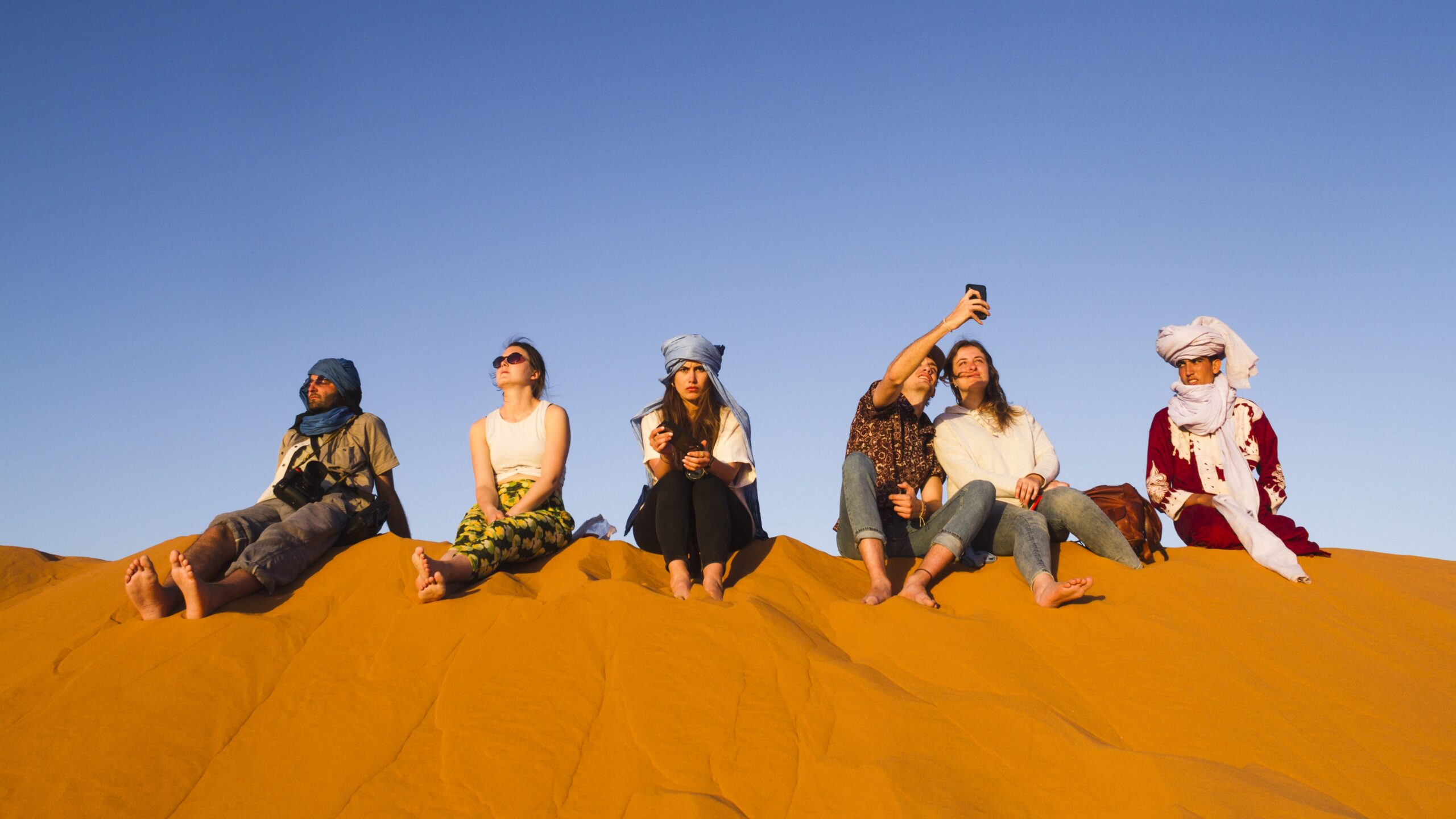 group-people-sitting-top-dune-sahara-morocco