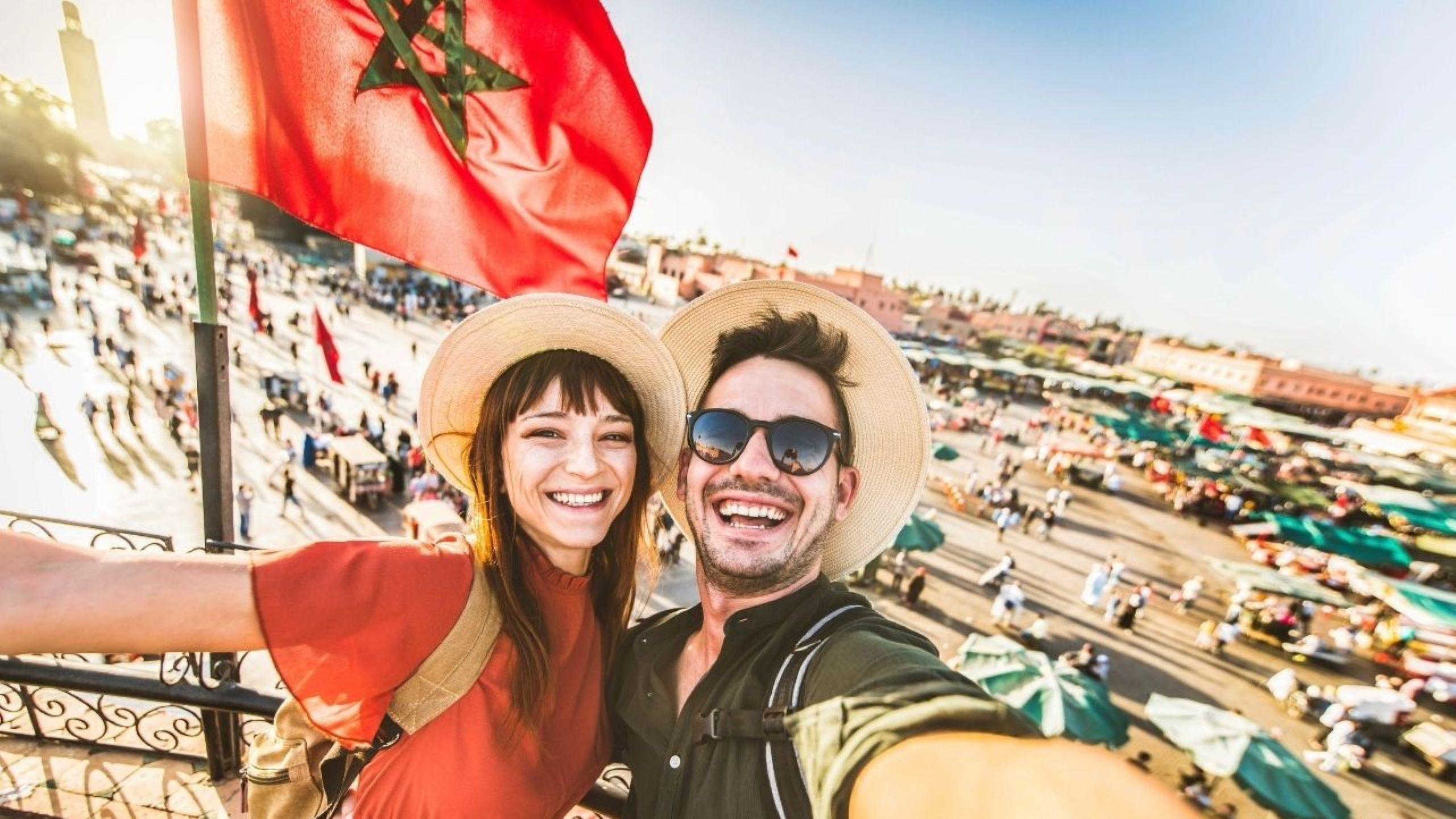 Tourists exploring colorful Marrakech medina souks during December winter getaway, browsing traditional spices, textiles, and handcrafted goods in comfortable mild weather
