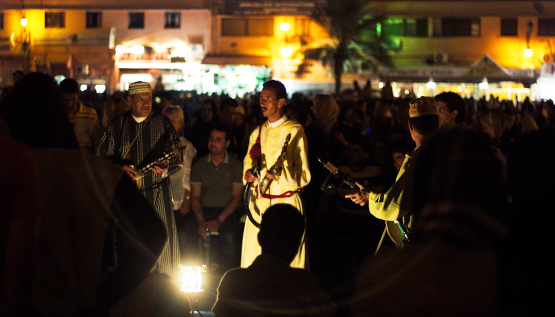 A maalem musician performing at the Morocco festival season in Essaouira, with a crowd gathered around the open-air stage