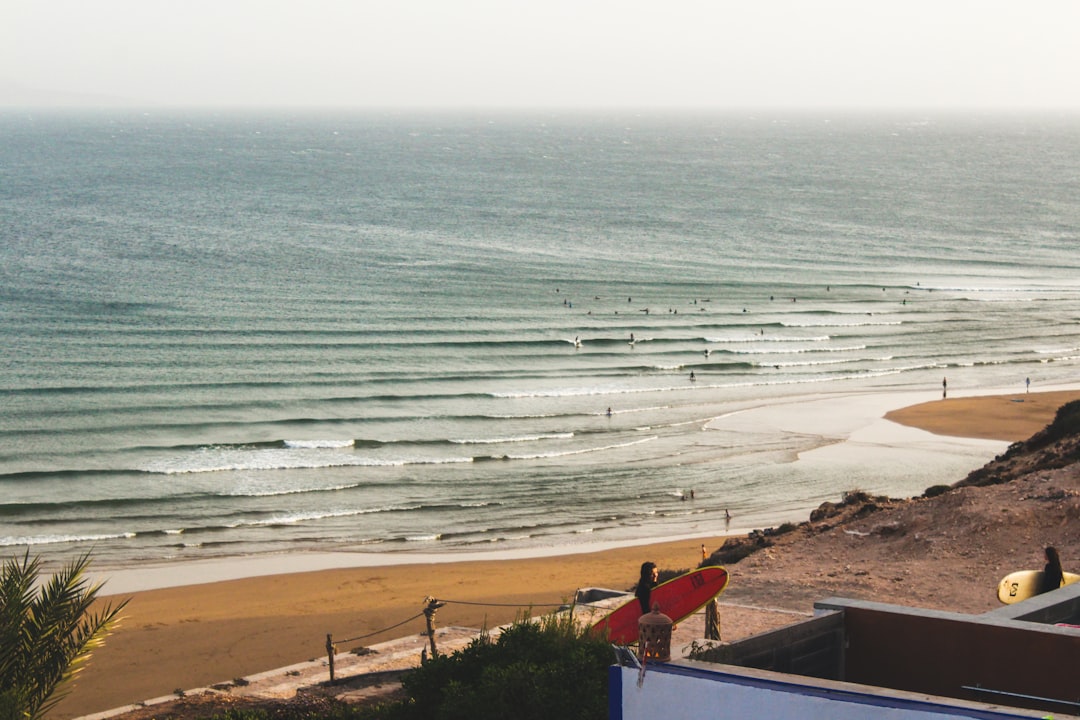 A surfer carries a board through a Moroccan village after a morning session, showing life when surfing Morocco in summer