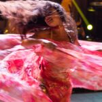 A performer in traditional costume on stage at the popular arts festival in Marrakech, surrounded by a crowd at night