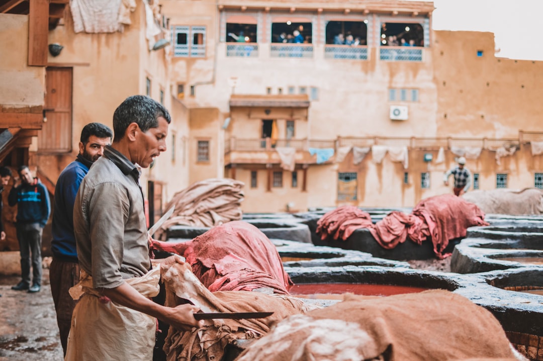 A skilled artisan in Morocco dips fabric into a natural dye vat, part of the handwoven textiles production process.