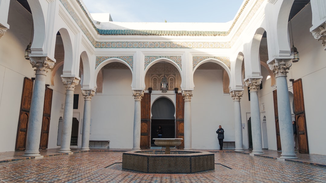 A person dressed in light cotton clothing rests in a shaded Moroccan riad courtyard during a morning wellness break