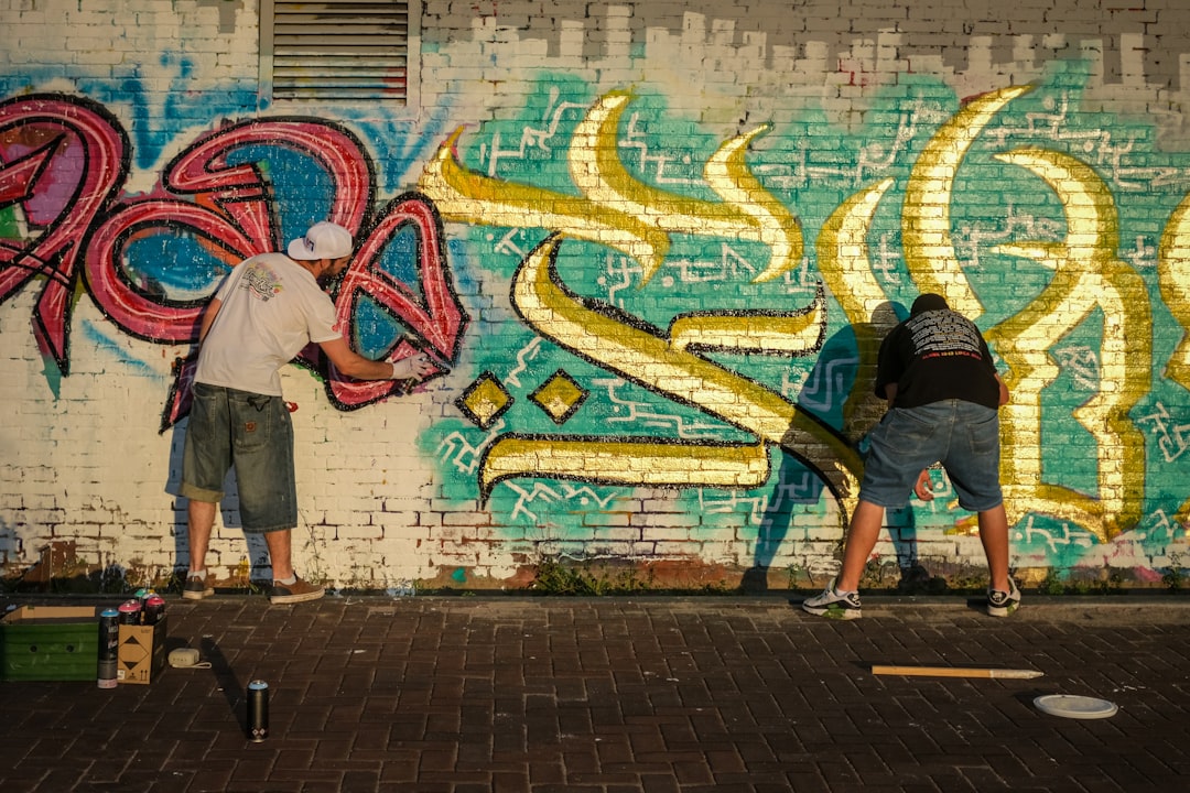 A Moroccan calligraphy designer applies bold Arabic letterforms to a large canvas in a bright studio