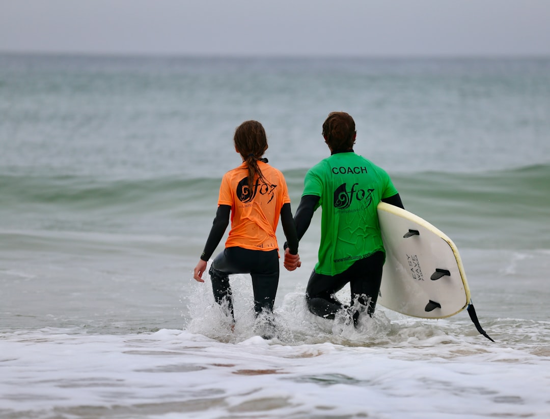 A surf instructor guides a beginner student into a wave, a scene typical of surfing Morocco camps in summer