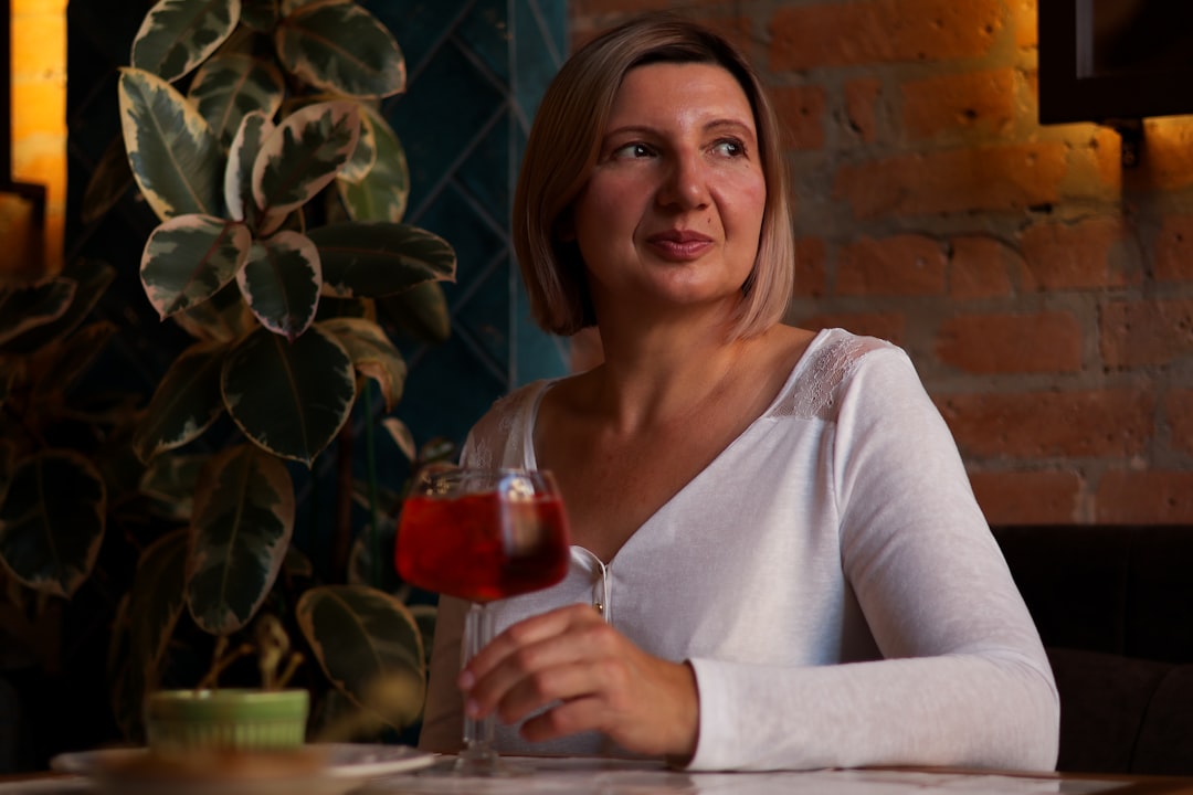 A smiling woman holding a bright red glass of hibiscus jus de bissap, one of the most popular cold Moroccan drinks in summer