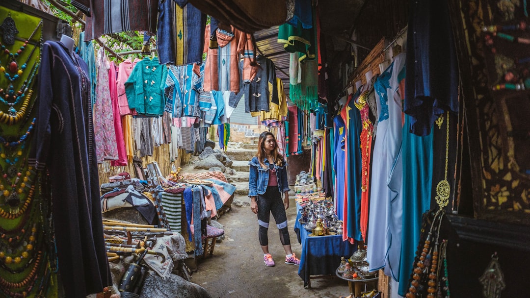 A woman selects handmade garments at a Marrakech boutique, exploring sustainable fashion in Morocco