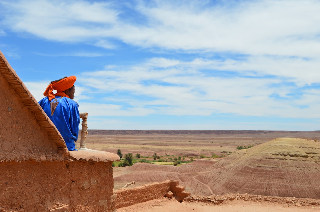 A woman rests on a guesthouse in one of the most scenic Moroccan mountain villages, with green valleys visible.
