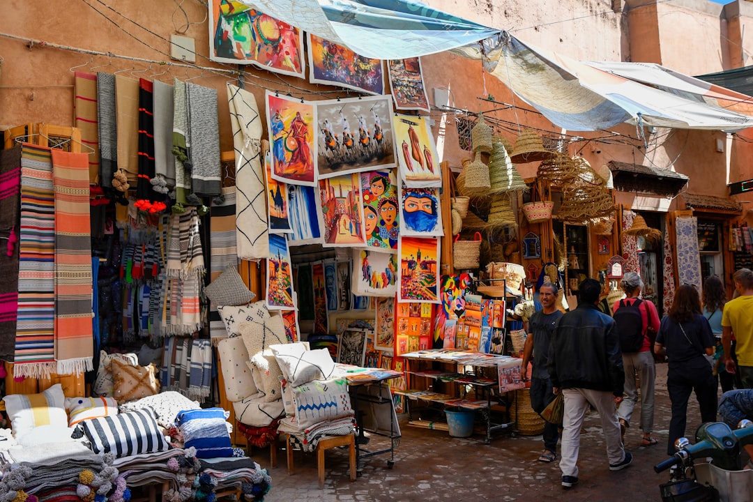 A muralist working on a large wall painting during the Asilah Moussem, with the whitewashed medina behind her