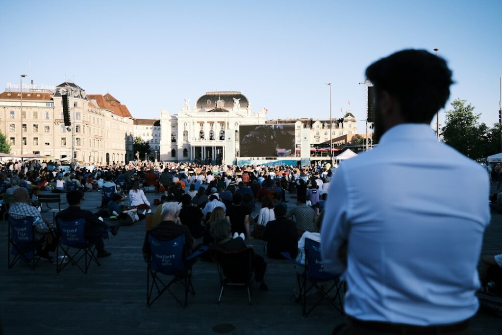 A Moroccan man in a crowd watches a public screen during the Throne Day national address in Morocco