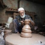 A Fassi artisan demonstrates Moroccan pottery hand-throwing technique on a foot-powered wheel in Ain Nokbi
