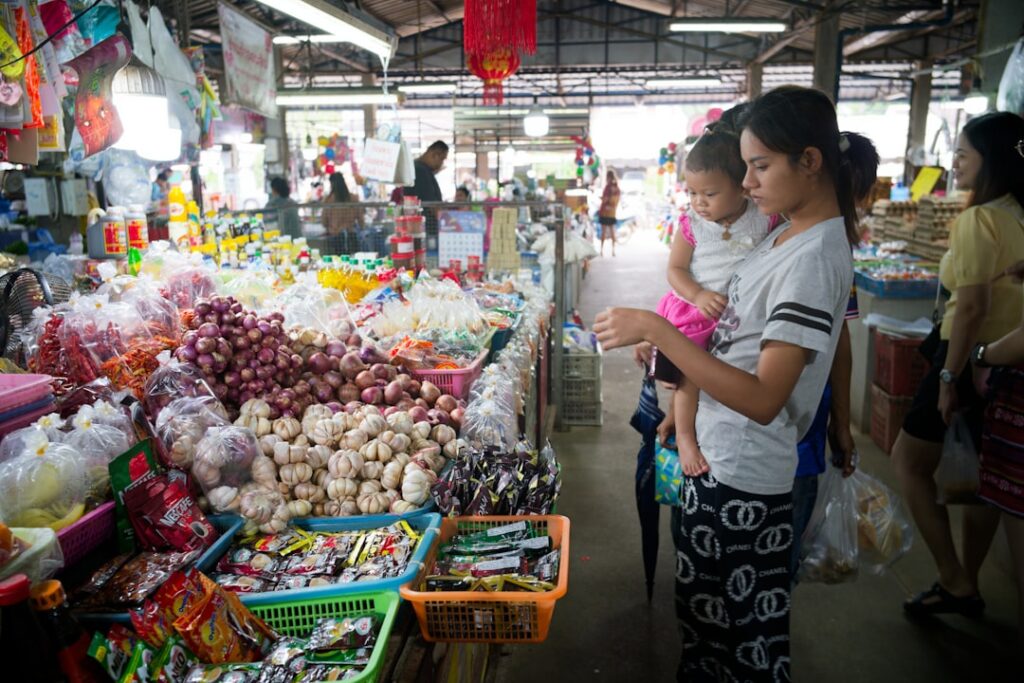 A mother and child selecting fresh vegetables together at a Moroccan souk, practicing Moroccan Arabic words for each item