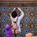 A Moroccan artisan woman arranging reclaimed zellige tiles to furnish a Moroccan home with medina materials