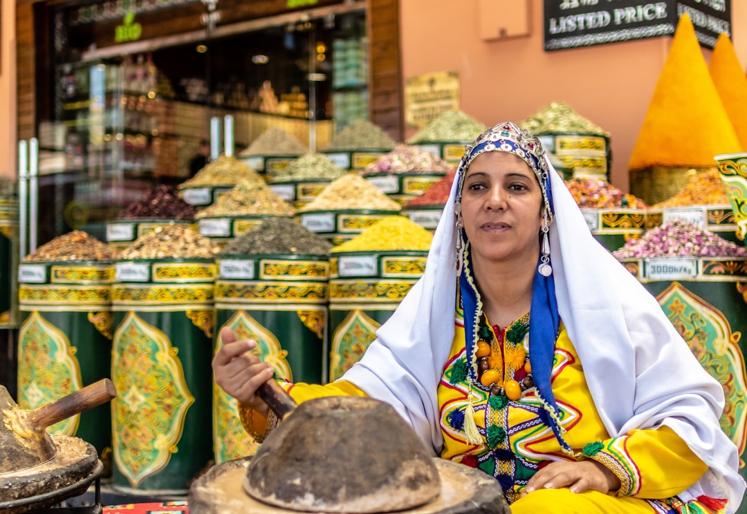 A woman choosing dried herbs at a Moroccan souk stall as part of her seasonal hammam reset routine